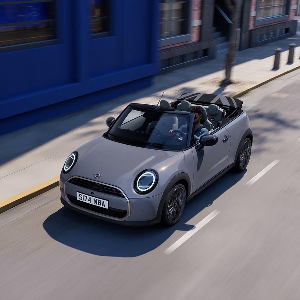 MINI Cooper Cabrio a circular numa estrada junto a edifícios azuis